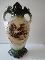 Full image of vintage ceramic vase with green and cream glaze, two handles, and painted country scene.