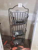 Three-tier metal rack with three removable wire baskets stacked vertically. The baskets are made of wire mesh and have handles. The rack is black metal and shows some dust and minor signs of use.