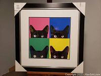 Framed and matted print showing the pop art style image of four black cats' faces with bright colored backgrounds inside a black frame.