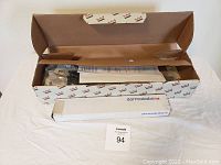 Opened cardboard box containing the Dormakaba ITS961 concealed door closer parts and installation instructions.