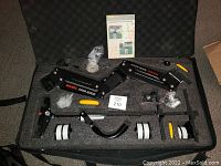 Wide view of FlyCam 6000 magic arm stabilization components with multiple white and black weights and instruction manual inside a foam padded case.