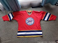 Red Hockey Night In Canada hockey jersey laid flat showing front and sleeve striping.