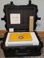 Inside of the black flight case showing the white HYTE Revolt 3 computer case with included documents and packaging box.