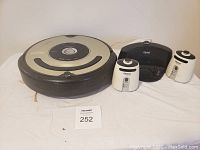 Full view of iRobot Roomba vacuum with two beacons and docking station on a white cloth surface.
