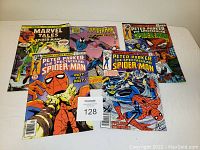 Five Spiderman comic books displayed on a white surface: Marvel Tales Spider-Man, Spider-Man Collins Preview, and three Peter Parker The Spectacular Spider-Man issues.
