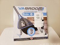 Front view of the VaBroom box showing product image and 2-in-1 function with built-in vacuum.