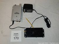 The lot showing the video spy camera, radio AV receiver, and power adapter arranged on a white surface.