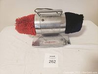 Full view of vintage Dremel shoe polisher with red and black polishing bonnets on either end.