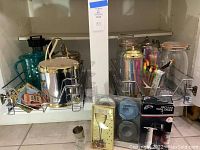 Two chrome slide-out racks containing mixed serveware: ice buckets, pitchers, mason jars, souvenir trays, coasters, thermometer and wine saver