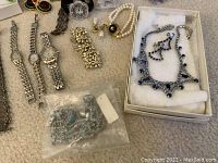 Photo showing multiple watches, bracelets, clip-on earrings, and boxed rhinestone necklace set.