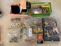Full lot overview showing multiple boxes and plastic bags containing costume jewelry including pearl necklaces, assorted earrings, and brooches.