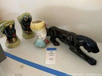 Overview of panther figurine and three head vases on white surface