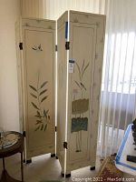 Full view of the four-panel painted screen standing in the room, showing art and hinges.