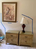 Photo of two solid wood nightstands side by side with a lamp on one and wall art hung above