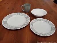 Photo of large plate, small plate, bowl, and gray mug on wooden table, showing pattern and style of dinnerware pieces.