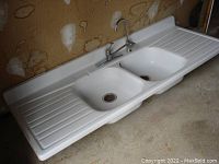 Front view of full sink showing both basins, drainboards, backsplash and faucet.