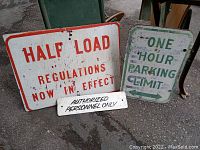 Three vintage signs displayed outdoors on pavement, showing wear and paint chipping.