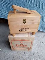 Wooden case labeled Ronson Roto-Shine Electric Shoe Polisher along with original cardboard box showing wear.