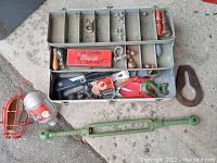 Open white toolbox displaying multiple vintage hand tools including sockets, pliers, and small hardware items.