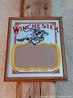 Front view of frame showing Winchester graphic with cowboy on horse in red, black, and yellow on mirrored background with an empty photo slot.