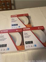 Three new in box Utilitech 2700K LED recessed retrofit downlights placed on a table.