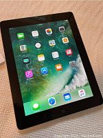 Apple iPad 4 tablet powered on showing iOS home screen with app icons.