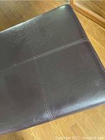 Top view showing brown faux leather surface with stitching detail on ottoman lid.