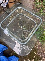 Top view showing clear square glass top with beveled edges and metal base with gold circular decorative elements.