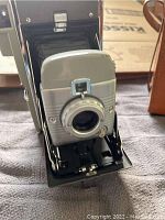 Front view of Polaroid Land Camera Model 80A showing lens plate and shutter dial.