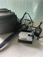 Sony Handycam HDD Video Camcorder SR42 placed on Sony charging dock with power adapter and cables alongside deluxe black carrying bag.