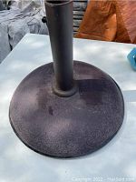 Top-down view of umbrella base showing round cast iron body with central cylindrical holder.