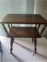 Front view of the vintage solid wood colonial table showing top and lower shelf with turned spindle legs.