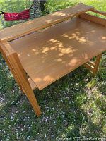 Top-down view of solid wood desk showing flat work surface and shadows from surrounding trees.