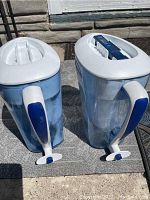 Two ZeroWater water filter pitchers placed side by side, showing front and handle sides, both have white lids with blue accents.