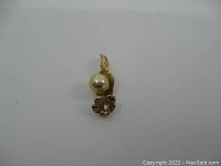 Front view of the vintage 10K gold pendant with pearl, showing floral motif and pearl detail.