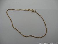 Full view of the delicate 10k gold bracelet or anklet laid flat to show length and chain style.