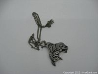 Front view of the orca pendant showing engraved Native Indigenous style design and attached chain.