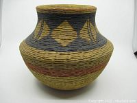 Front view of the pottery vase showing the overall shape and basket weave texture with painted geometric patterns.