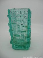 Front and side view of a green glass vase with geometric raised pattern and rectangular shape.