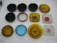 Top-down view of a variety of vintage casino ashtrays arranged in rows displaying different colors and casino logos.