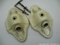 Pair of cream-colored ceramic vintage ceiling light fixtures with ribbed texture and colorful floral designs, showing sockets and mounting hardware.