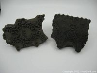 View of the tops of both hand carved wooden fabric stamps showing intricate floral and circular design patterns and the irregular edges of each stamp.