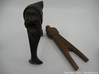 Two wooden nut crackers on white background, one shaped like a gnome elf and the other a folk art style piece.