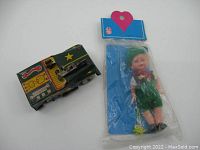 Photo showing lot of two vintage toys: green tin toy jeep with driver figure and Sleepy eye doll in sealed original packaging.