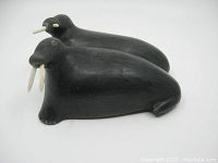 View of the two walruses carved from black soapstone showing detailed tusks and eyes.