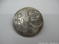 Front view of the brooch showing the detailed indigenous hand carved design.