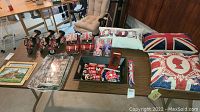 Photo displaying British-themed pillows, salt and pepper shakers, trays, and souvenirs arranged on a table.
