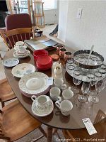 Wide view of dishware, glassware, copper mugs and punch set displayed on table.