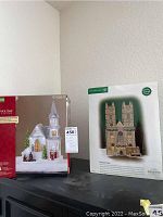 Photo showing boxed set of two holiday village pieces: Department 56 Westminster Abbey and an animated musical church scene.
