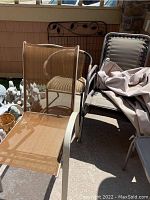 Two tan mesh sling chairs with metal frames and two black metal frame chairs with padded seats and backs, partially covered by a beige cloth.